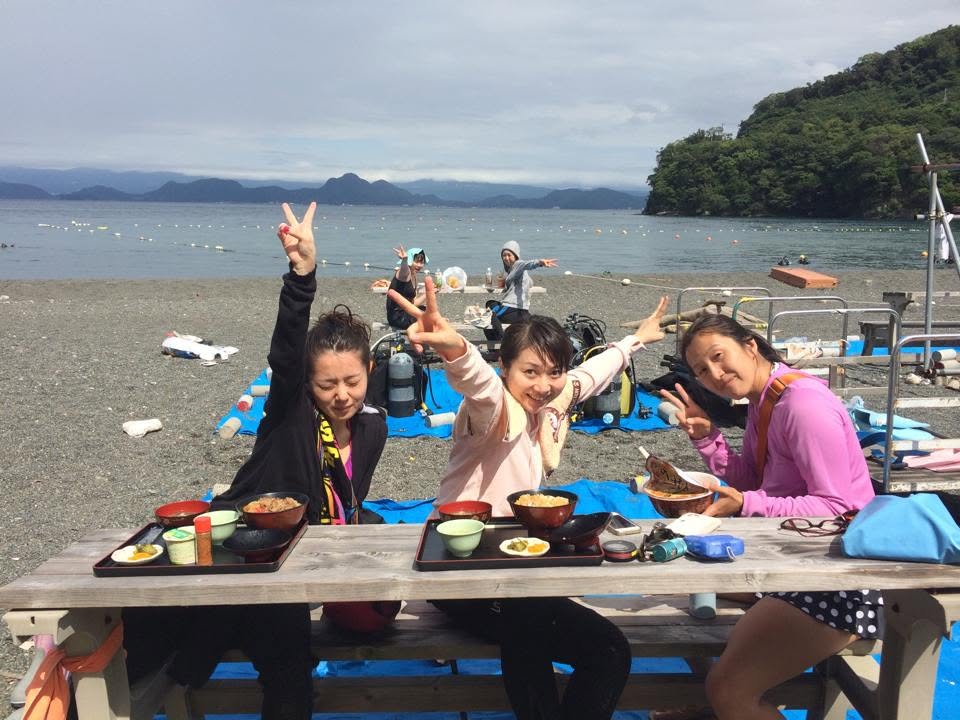 海辺のテーブルで食事を囲む参加者(2015年)