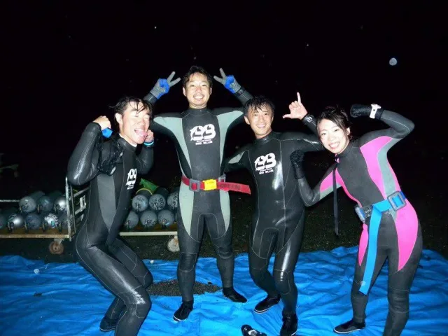 夜の海辺でウェットスーツ姿で並ぶ参加者(2012-2013年)