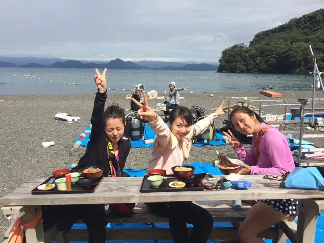 海辺のテーブルで食事を囲む参加者(2015年)