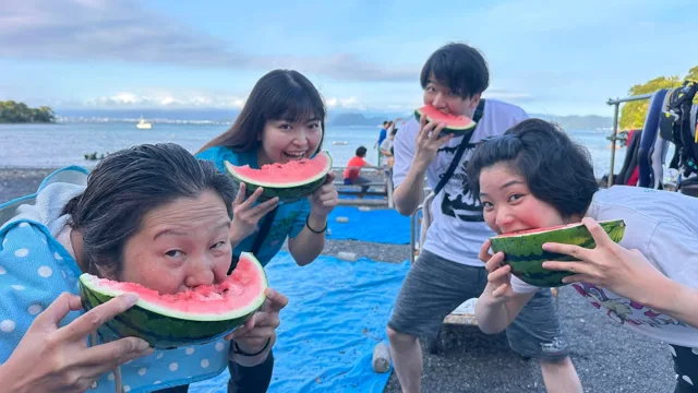 海辺でスイカを食べる4人の参加者
