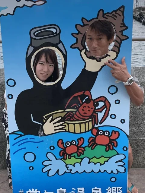 ダイビングのイラストが描かれた顔出しパネルと参加者