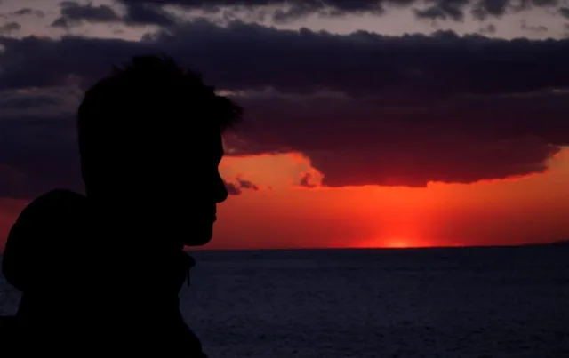 大島の海に沈む夕日を背景にした人物のシルエット（ツアー中と推定）