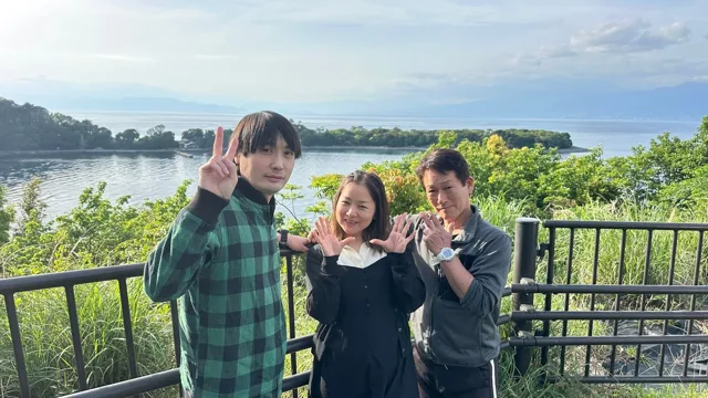 伊豆・大瀬崎でのダイビング：海を背景に記念撮影する3人のツアー参加者