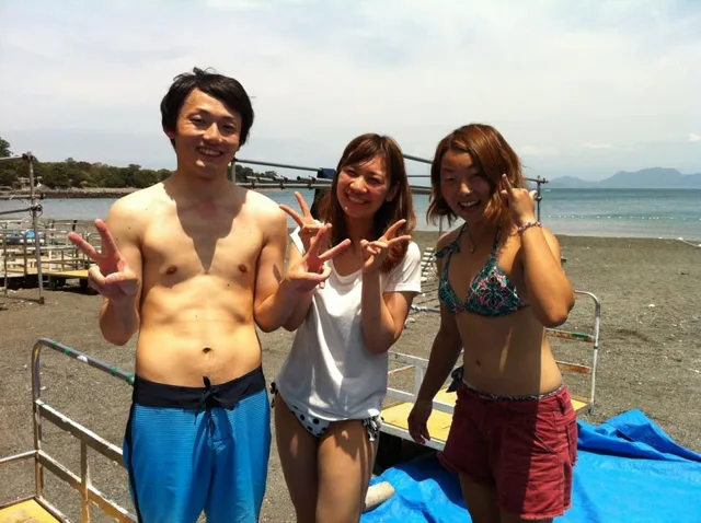 伊豆・大瀬崎でのダイビング:晴天の大瀬崎で海を背に記念撮影する3人のダイビング参加者