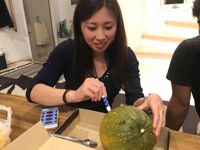 BIG BLUEの店内で丸い果物に顔の飾りを作る参加者