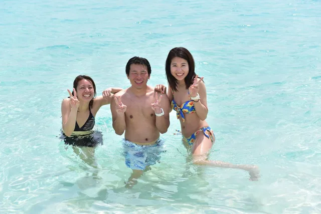 沖縄県・宮古島での宮古島ダイビングツアー中、透明な浅瀬で並ぶ3人の参加者