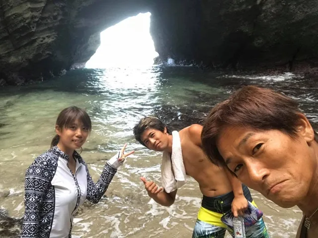 静岡県下田市・竜宮窟での雲見ツアー中、竜宮窟の浜辺で記念撮影する3人の参加者