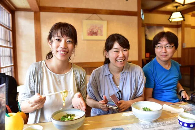 飲食店名・撮影場所未確認（越前ツアー）での越前ツアーの食事で料理を前に並ぶ3人の参加者