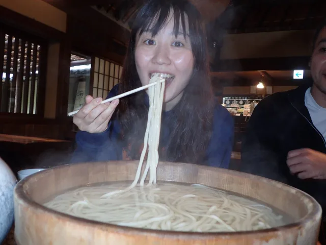 飲食店名・撮影場所未確認（四国観光ツアー）での四国観光ツアーの食事で大きな桶のうどんを味わう参加者