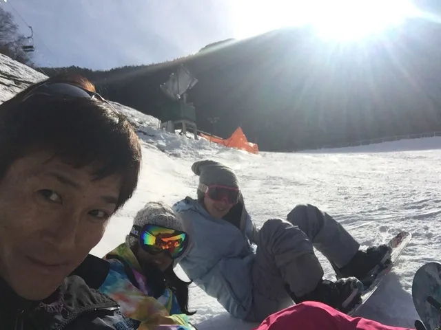富士山周辺での富士山へのスキー行事で雪上に座り記念撮影する参加者