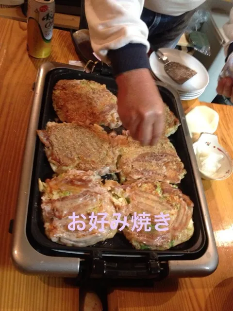 ツアー中の食事（同日写真から推定）でのツアー中の鉄板でお好み焼きを焼く様子。同日の参加者と服装から同じツアーと推定